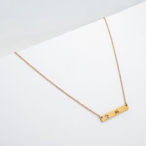 Kaklo papuošalas gaLiu su plokštele, išpjauta žvaigžde ir auksinės spalvos grandinėle ant balto fono.