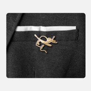 Aukso spalvos ženkliukas gaLiu prisegtas prie tamsios švarko kišenės matomomis emalio detalėmis